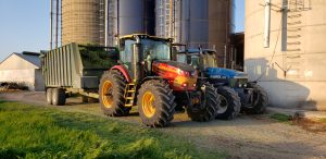 Versatile 255 pulling a silage cart with New Holland Tractor at silos